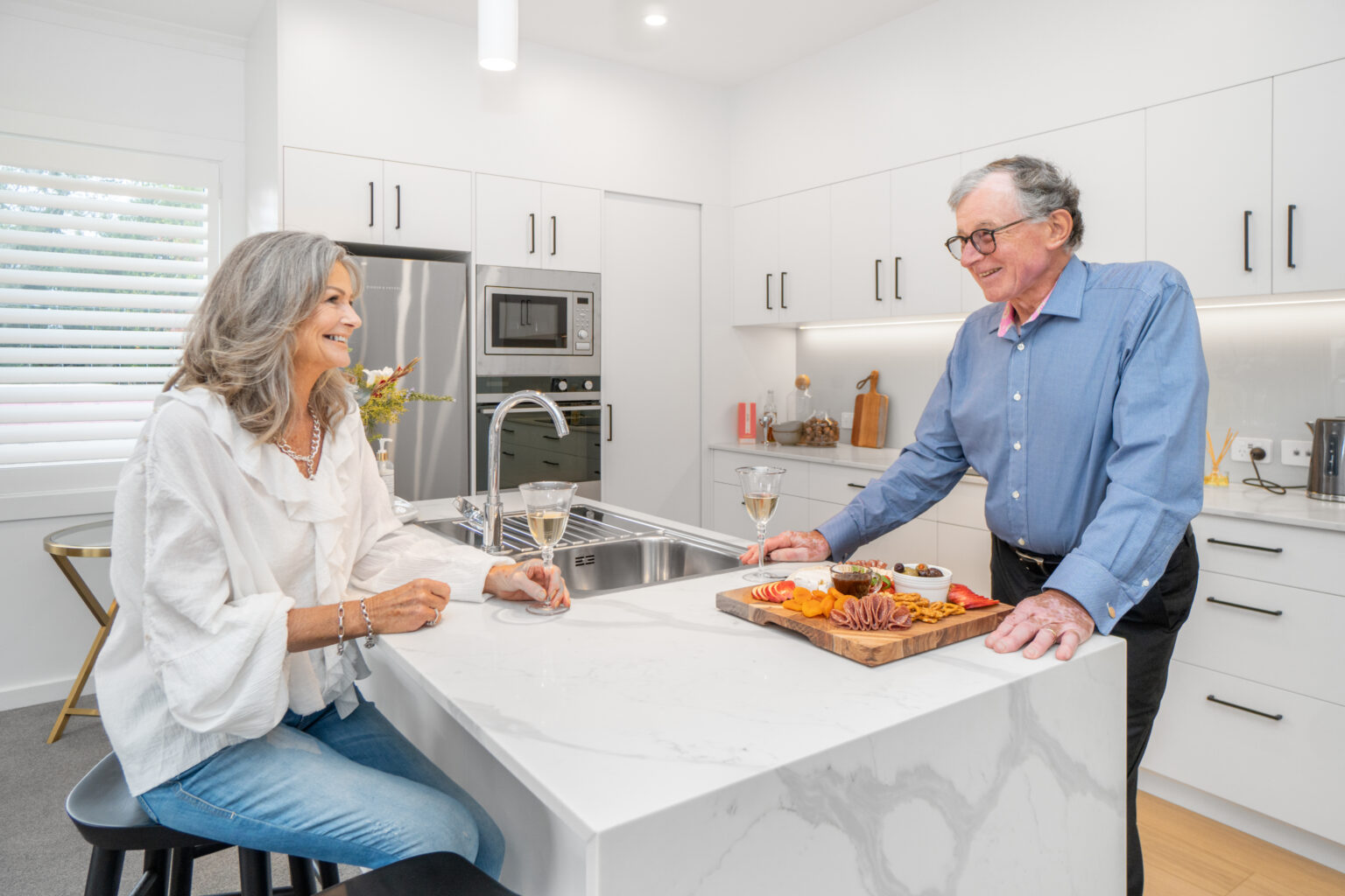 Man and woman sitting at kitchen bench talking