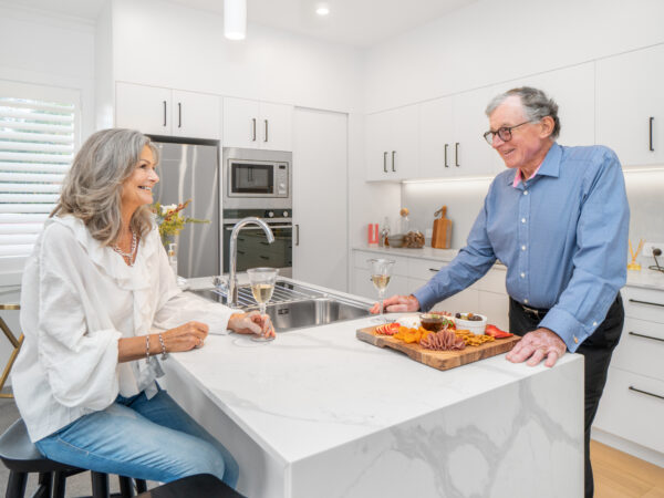 Man and woman sitting at kitchen bench talking