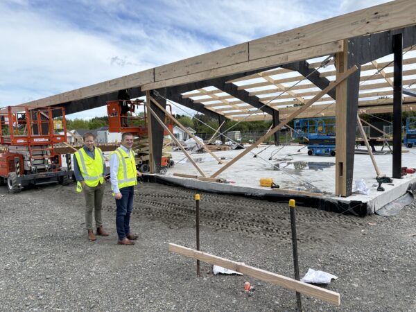 Two men dressed in hi viz standing in front of a new building frame